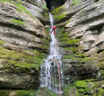 Descente en rappel dans cascade qui ressort de la grotte